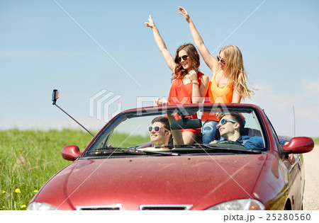friends driving in cabriolet car and taking selfie 25280560