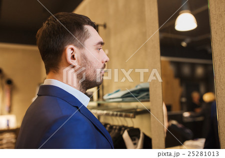 man in jacket looking to mirror at clothing store 25281013