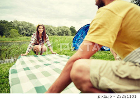 happy couple laying picnic blanket at campsite 25281101