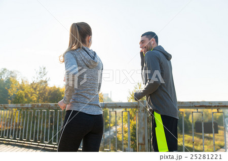 happy couple with earphones running outdoors 25281221