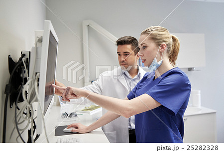 dentists with x-ray on monitor at dental clinic dentists with x-ray on monitor at dental clinic 25282328