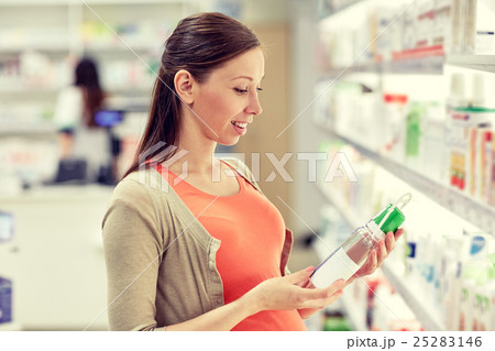happy pregnant woman choosing lotion at pharmacy 25283146
