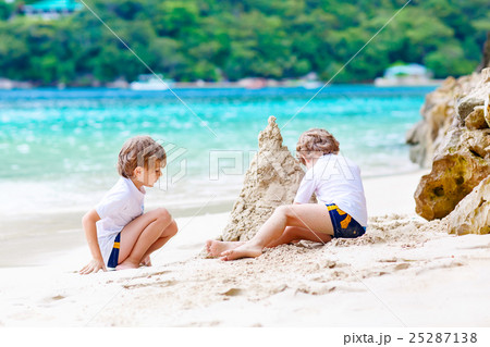 Two kid boys building sand castle on tropical Two kid boys building sand castle on tropical 25287138