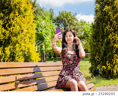 young girl making selfie sitting on a park bench young girl making selfie sitting on a park bench 25290205