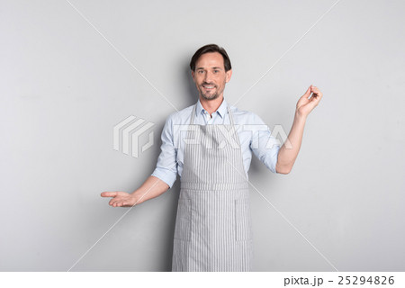 Handsome man standing on grey background in apron 25294826