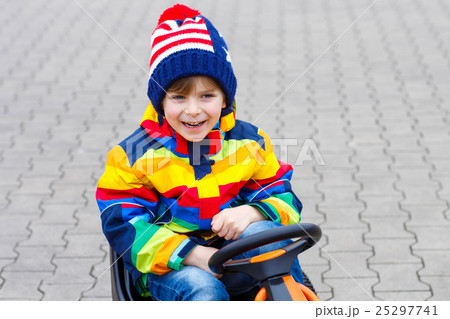 Little kid boy having fun on toy race car outdoors 25297741
