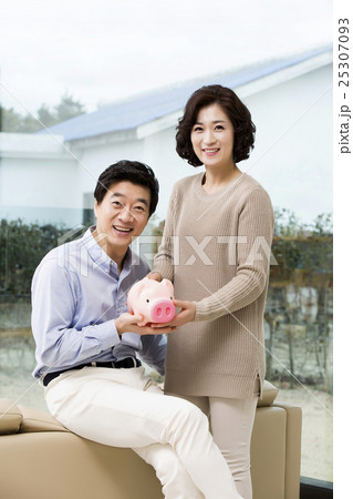 Happy Middleaged Asian Couple Holding a Piggy Bank 25307093