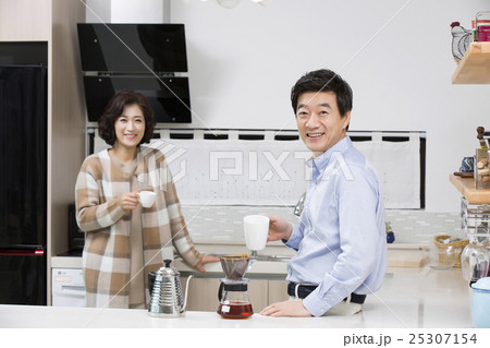 Middleaged Asian Couple Having Coffee in Kitchen 25307154