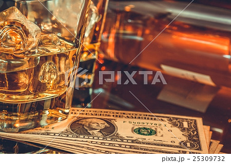 close-up of glasses of whiskey near bottle and dollars on a black table. Western theme style 25309732