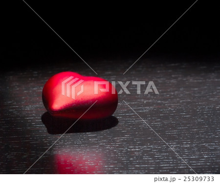 one decorative red heart on black dark light and on wood table, concept of valentine day 25309733
