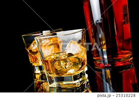 two whiskey with ice in glasses near bottle on black background two whiskey with ice in glasses near bottle on black background 25310228
