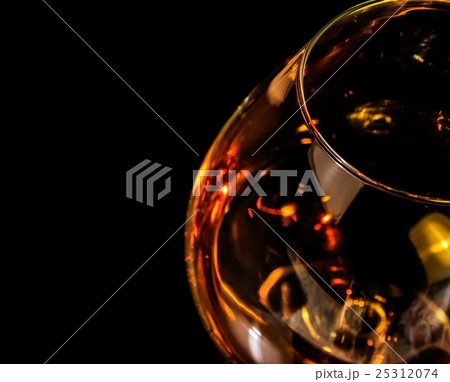 top of view of snifter of brandy in elegant typical cognac glass on black background with red reflection 25312074
