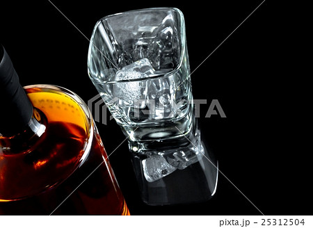 top of view of empty whiskey glass with ice near bottle on black background 25312504