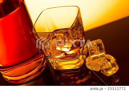 top of view of glass of whiskey near bottle with ice cubes on black table with reflection top of view of glass of whiskey near bottle with ice cubes on black table with reflection 25312772