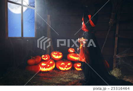 Halloween. child little witch with pumpkin  by the window waitin 25316464