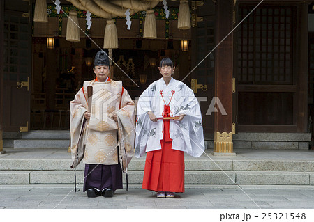 境内に立つ神主と巫女の写真素材