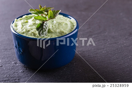 Blue bowl with wasabi dip with piece of herb 25328959