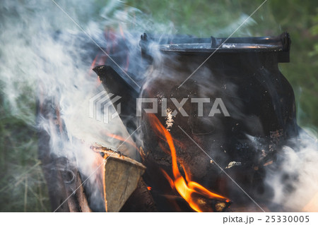 Teapot with boiling water stands on a bonfire Teapot with boiling water stands on a bonfire 25330005