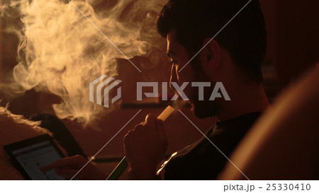 man smokes a hookah and uses tablet 25330410