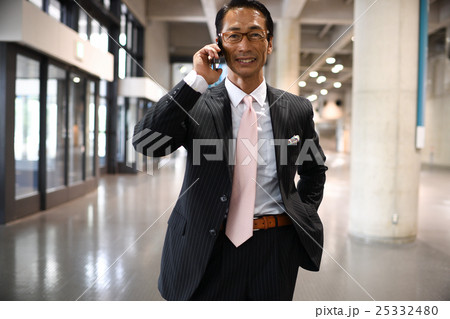 打ち合わせの電話　外出先で電話応答する男性　電話　ビジネスマン　 25332480