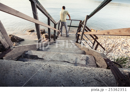 Young man stands on old wooden stairway 25362351