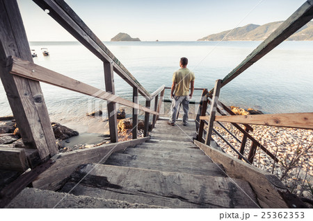 Man stands on old wooden stairway, sea coast Man stands on old wooden stairway, sea coast 25362353