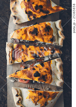 Sliced calzone on the stone background top view Sliced calzone on the stone background top view 25365658