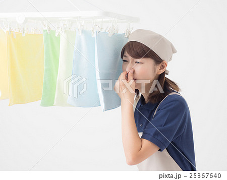 室内干しした洗濯物が臭くて鼻をつまむ女性の写真素材