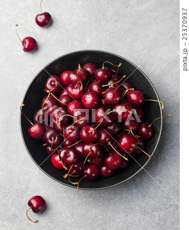 Fresh ripe black cherries in a black bowl Top view 25370937