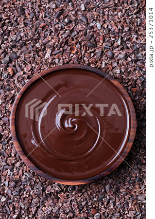Bowl of melted chocolate on a crushed cocoa beans 25371014