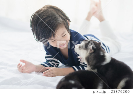 Cute asian child playing with siberian husky puppy 25376200