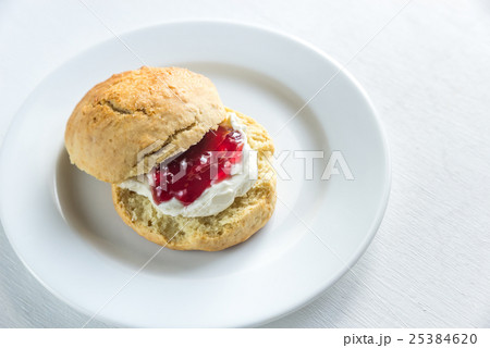 Scone with cream and cherry jam on the plate Scone with cream and cherry jam on the plate 25384620