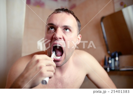 Man brushes teeth in bathroom an electric brush 25401383