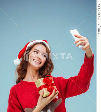 Girl dressed in santa hat with a Christmas gift 25407435