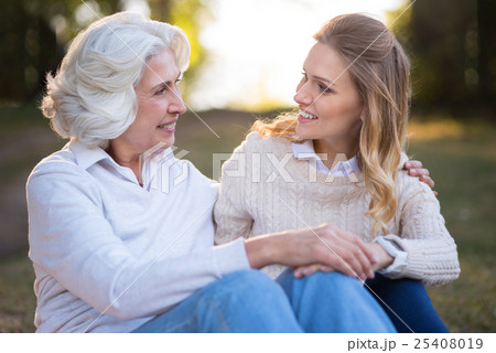 Two charming smiling women hugging and sitting on 25408019