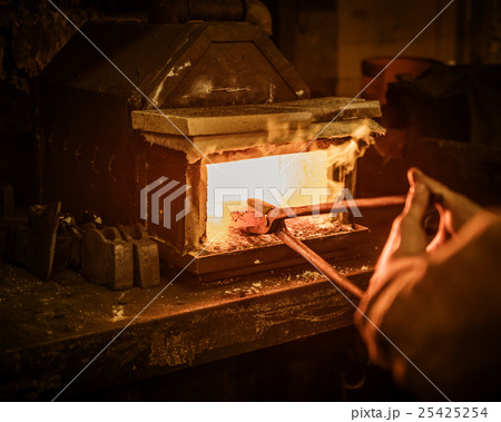 Senior blacksmith heats item before forging in 25425254