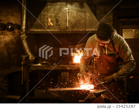 The blacksmith forging the molten metal on the The blacksmith forging the molten metal on the 25425297