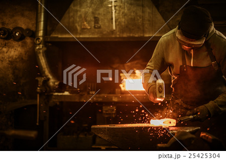 The blacksmith forging the molten metal on the The blacksmith forging the molten metal on the 25425304