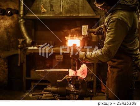 The blacksmith forging the molten metal on the 25425308