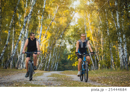 Two mountain bikers riding bike in the forest Two mountain bikers riding bike in the forest 25444684