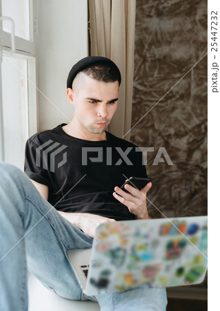 Man in black hat using laptop 25447232