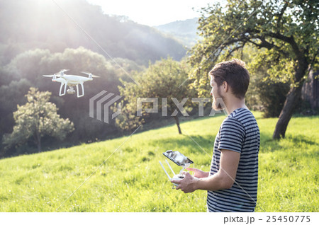 Young hipster man with flying drone. Sunny green Young hipster man with flying drone. Sunny green 25450775