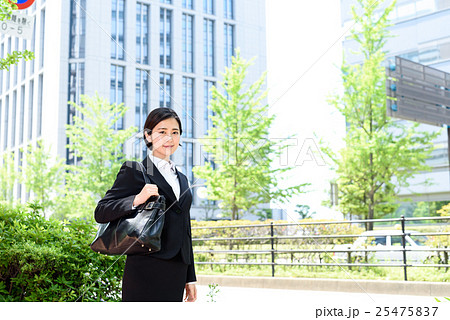 緑の綺麗なオフィス街を歩く若い会社員の女性　ビジネスウーマン 25475837