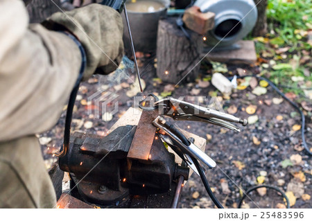 Welder welds iron ring by point electric welding Welder welds iron ring by point electric welding 25483596