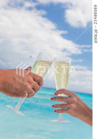 Clanging glasses with champagne at sandy beach Clanging glasses with champagne at sandy beach 25486069