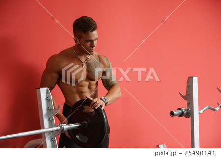 At gym. Image of bodybuilder standing near barbell 25490141