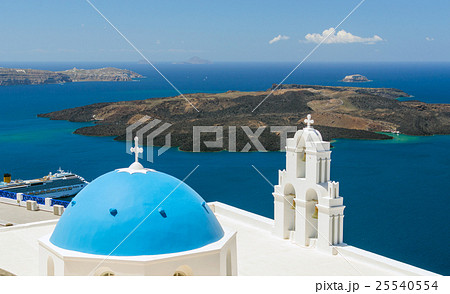 Blue-domed chapel with ochre bell tower in Oia 25540554