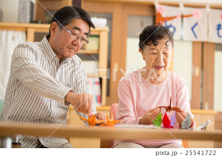 介護施設のリクエーションルームで折り紙を楽しむ二人のお年寄り 25541722