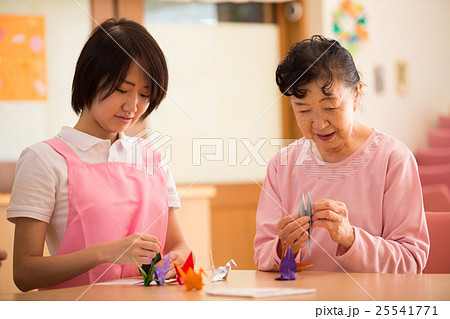 デイサービスで折り紙を楽しむおばあさんと介護福祉士 25541771