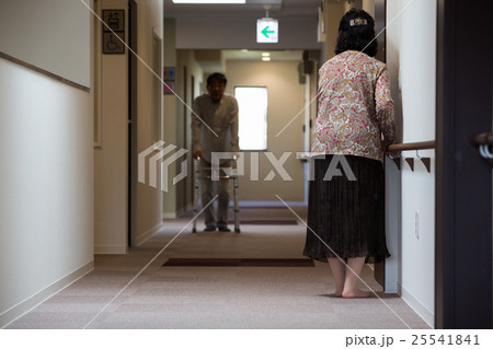 老人ホームの廊下を手するにつかまりながら歩くお年寄り 25541841